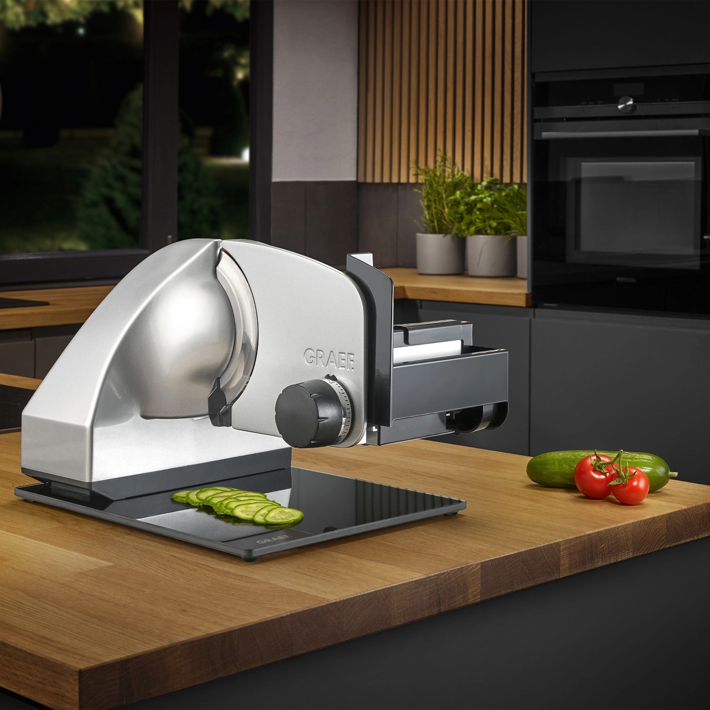 Electric slicer with vegetables on a wooden surface in a kitchen setting.