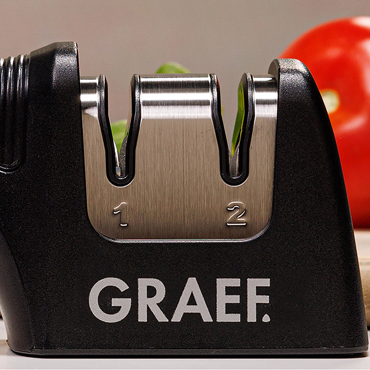 Un aiguiseur de couteaux Graef avec les numéros 1 et 2, à côté d'une tomate rouge.