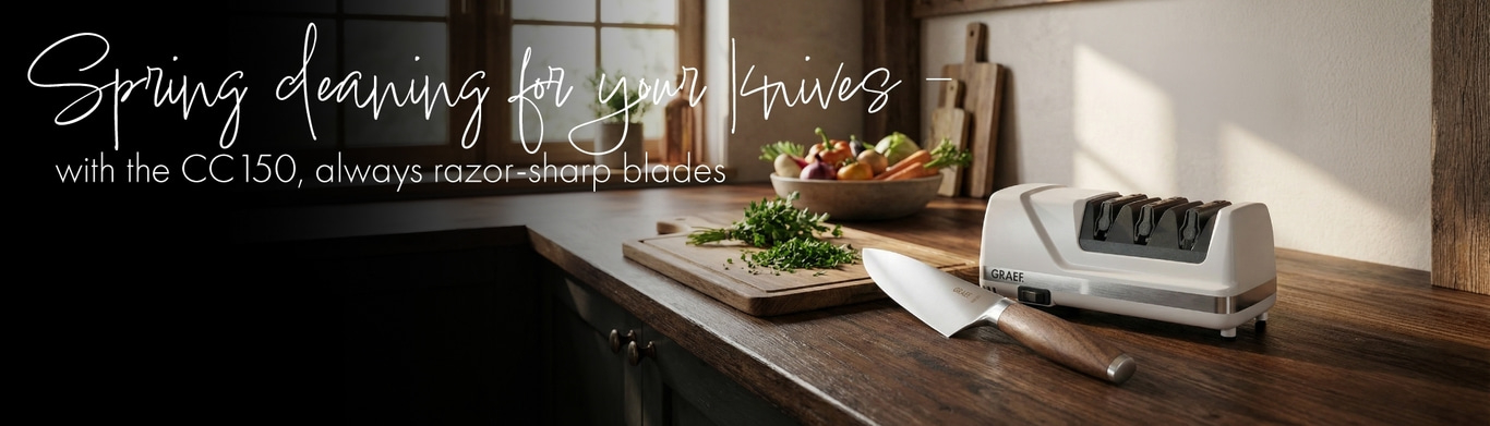 A GRAEF knife sharpener sits on a wooden surface next to a knife and vegetables.