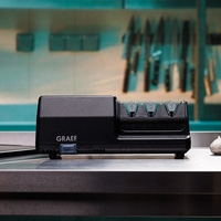 Affilacoltelli nero con logo GRAEF e numeri 1, 2, 3 sopra, su una superficie metallica.