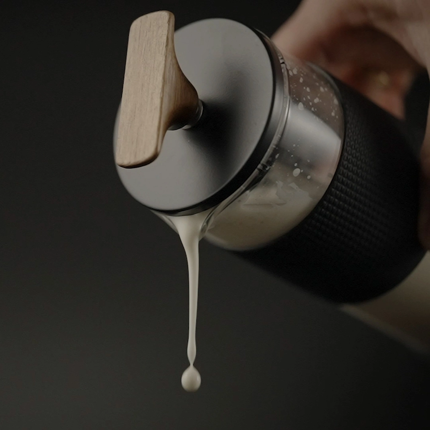 Une poignée en bois laisse couler un liquide blanc d'un récipient.