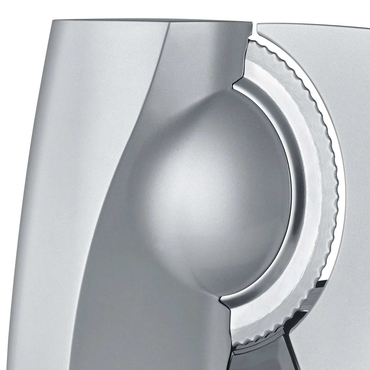 Close-up of a silver meat slicer with a serrated blade and smooth surface, modern design