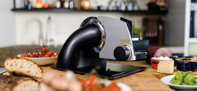 Graef slicer with tomatoes, bread, cheese and sausage on a wooden table