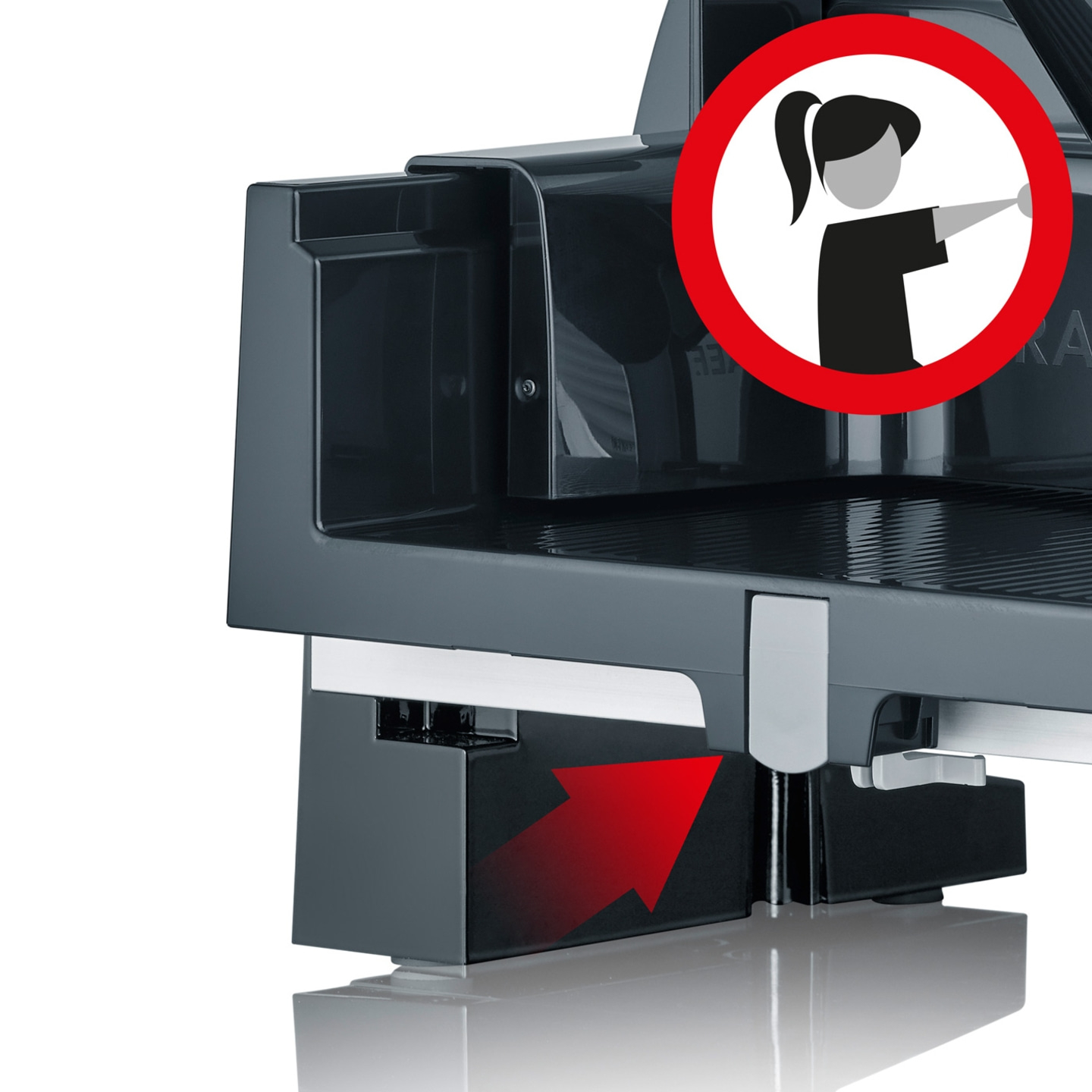 Primo piano di un'affettatrice elettrica con un segnale di avvertimento e una freccia rossa.