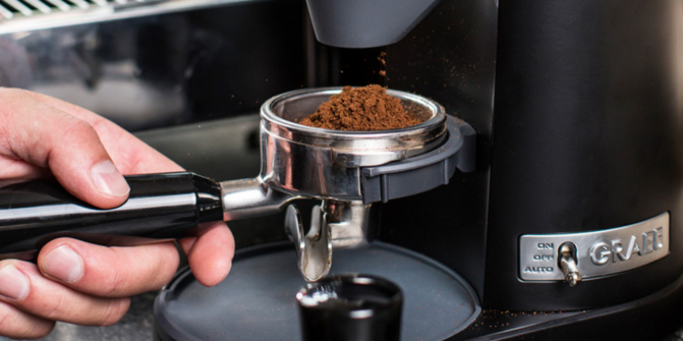 Macchina da caffè con caffè appena macinato che cade nel portafiltro.