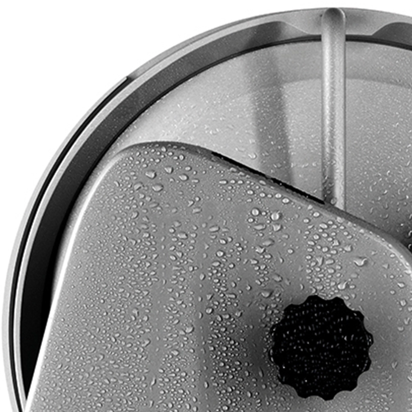 Gros plan d'une surface métallique grise avec des gouttelettes d'eau et un bouton noir.