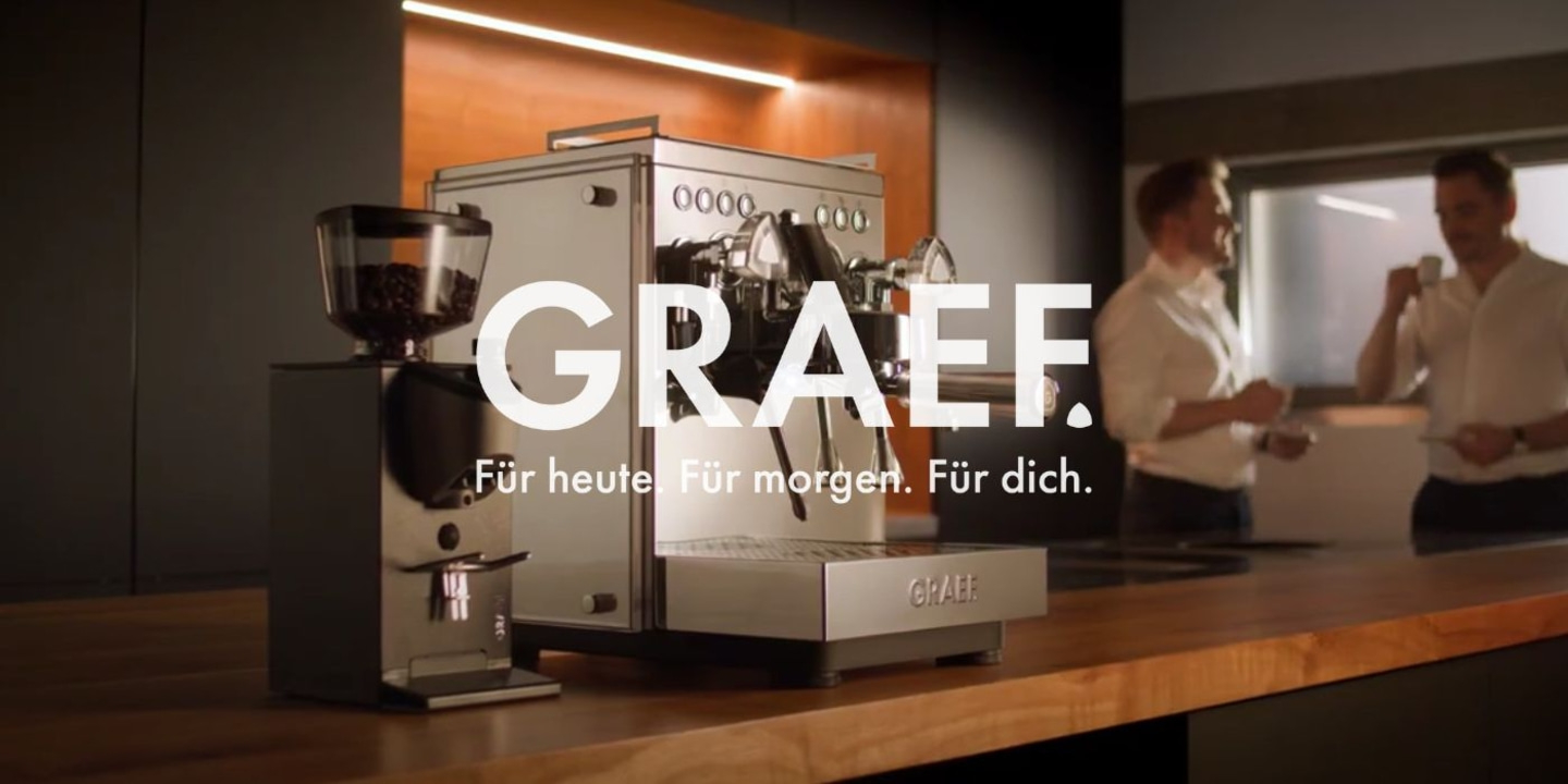 Machine à café GRAEF avec deux hommes buvant du café dans une cuisine