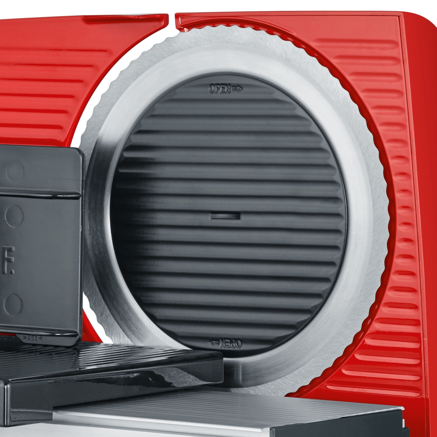 Close-up of a red meat slicer showing the blade and controls.