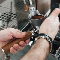 Mains tenant un filtre à café avec du café moulu dans une machine à café.