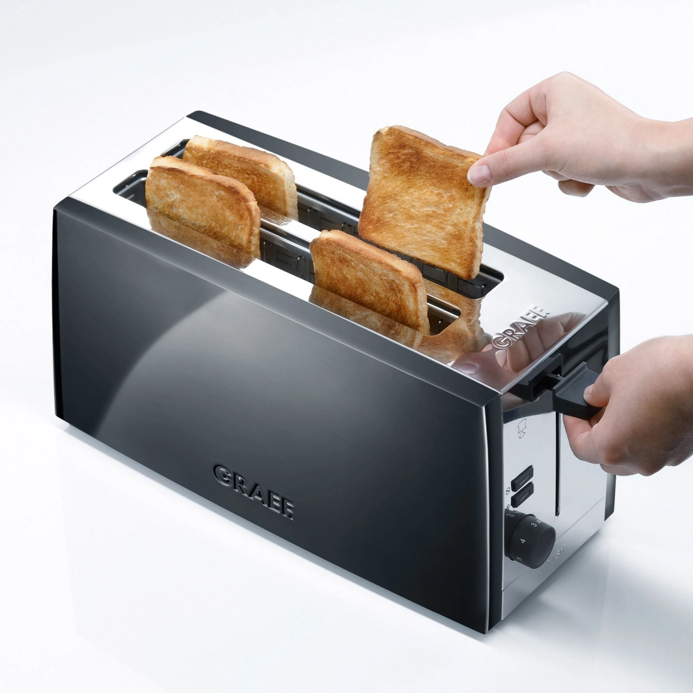 A toaster with toast, a hand removing toast, a knob is visible, shiny surface.