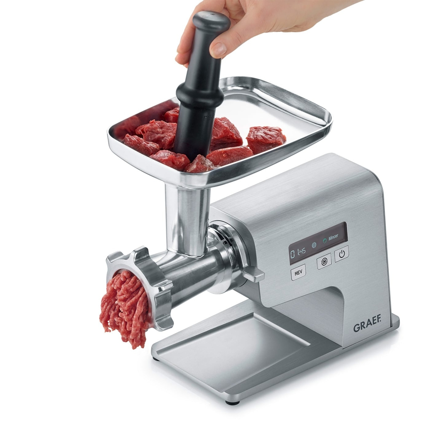 Meat grinder with meat and hand using a tamper to process meat for cooking.