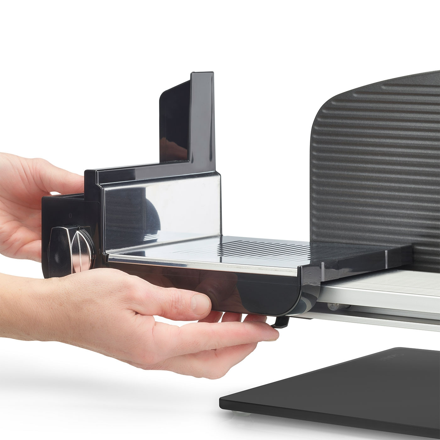 Primo piano di una persona che tiene un'affettatrice di carne nera isolata su sfondo bianco.