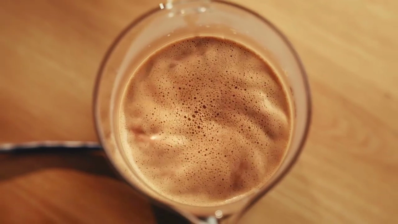 Café dans un verre, vu de dessus, sur une table en bois avec des bulles