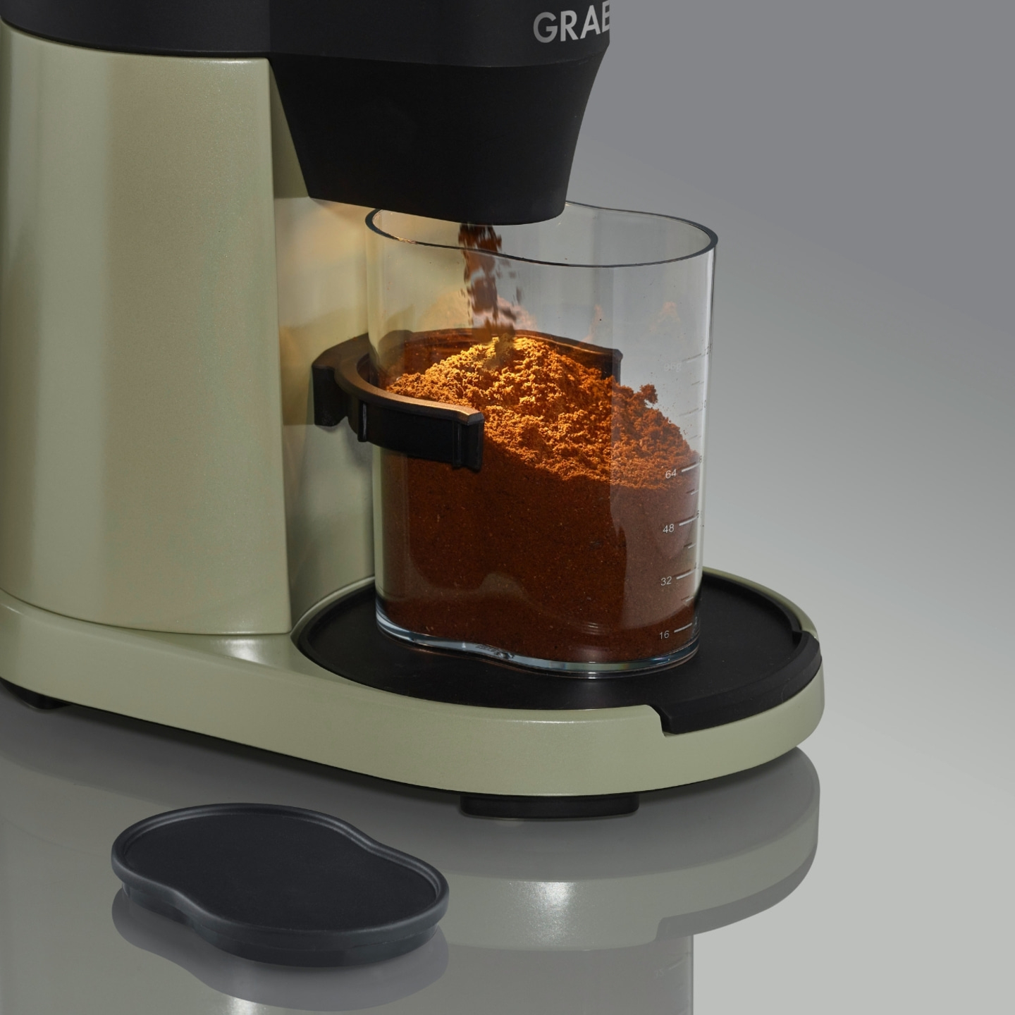 Coffee machine with coffee grounds, glass container, gray background, close-up shot