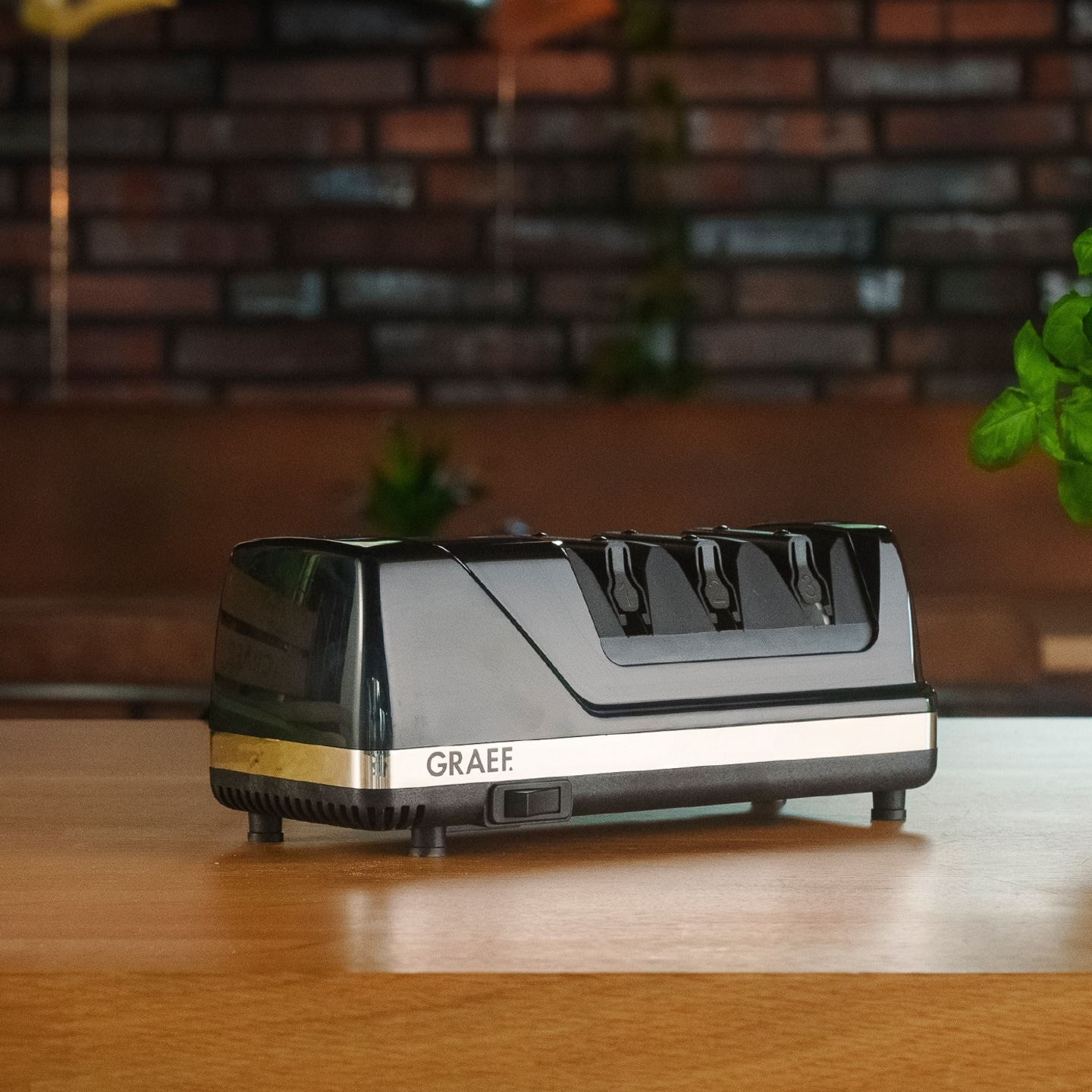 Black electric knife sharpener on a wooden table with the GRAEF logo.