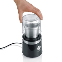 Hand opening coffee grinder with transparent lid and black body.