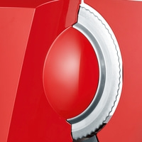 Close-up of a red food slicer with a serrated metal blade.