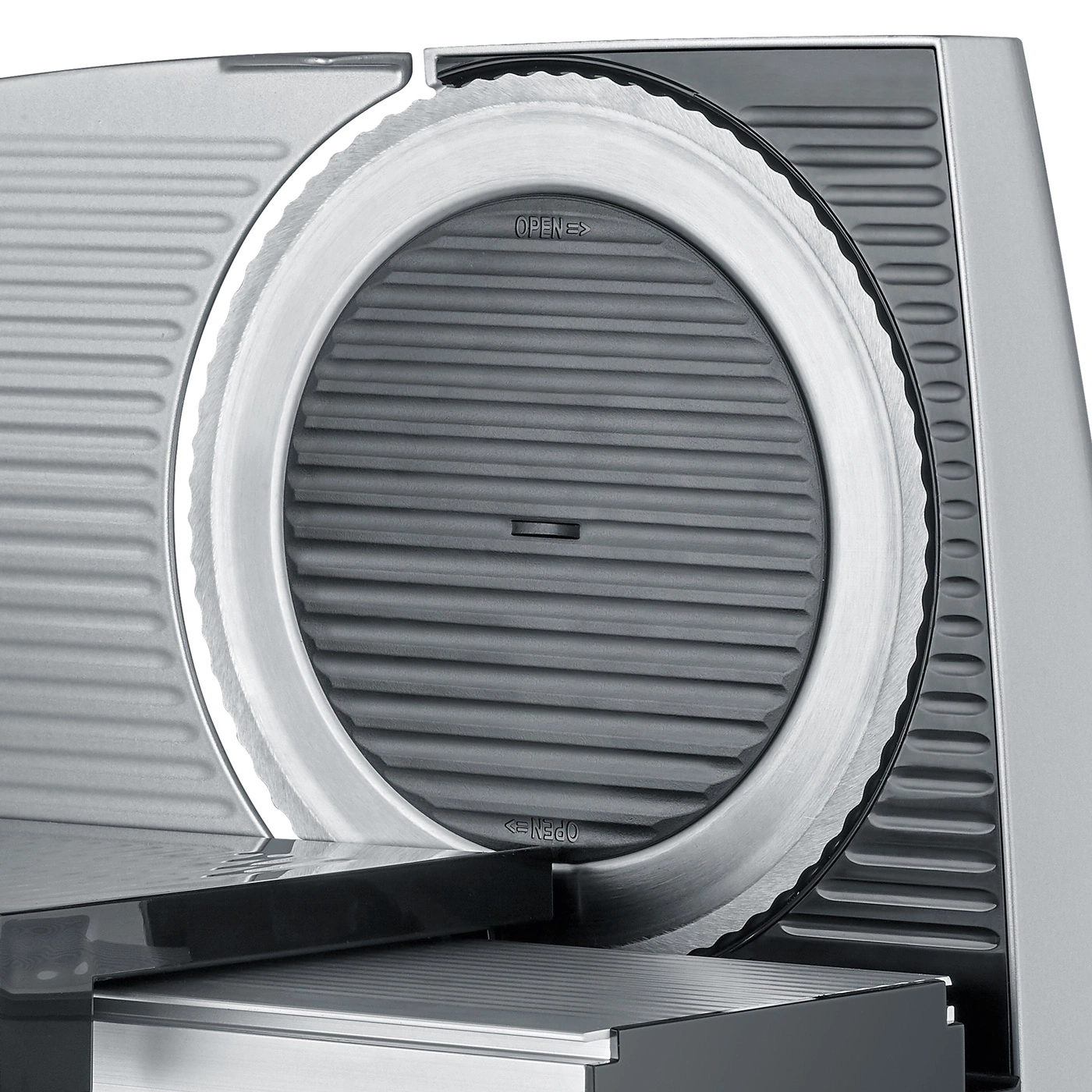 Close-up of a silver meat slicer with a circular blade and the word "OPEN" printed on it.