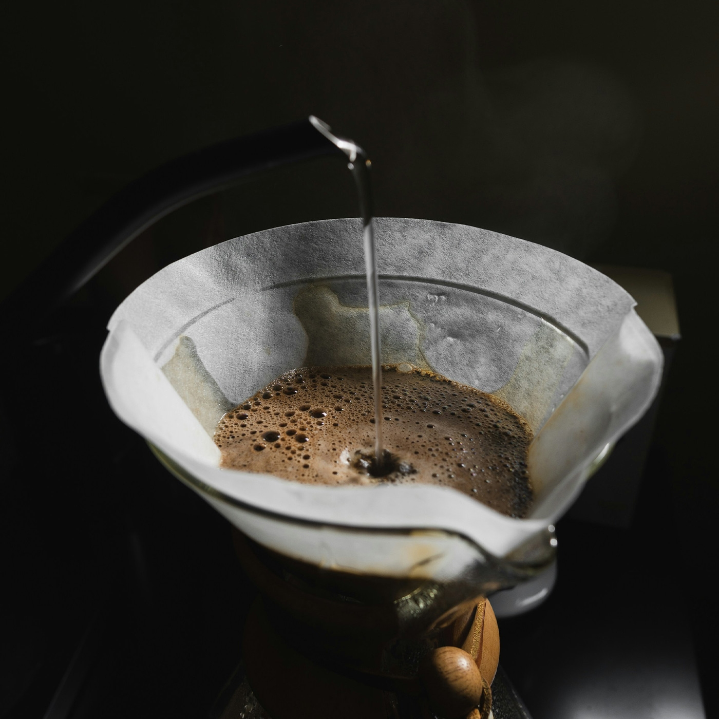 Eau chaude versée à travers un filtre à café dans une carafe en verre.
