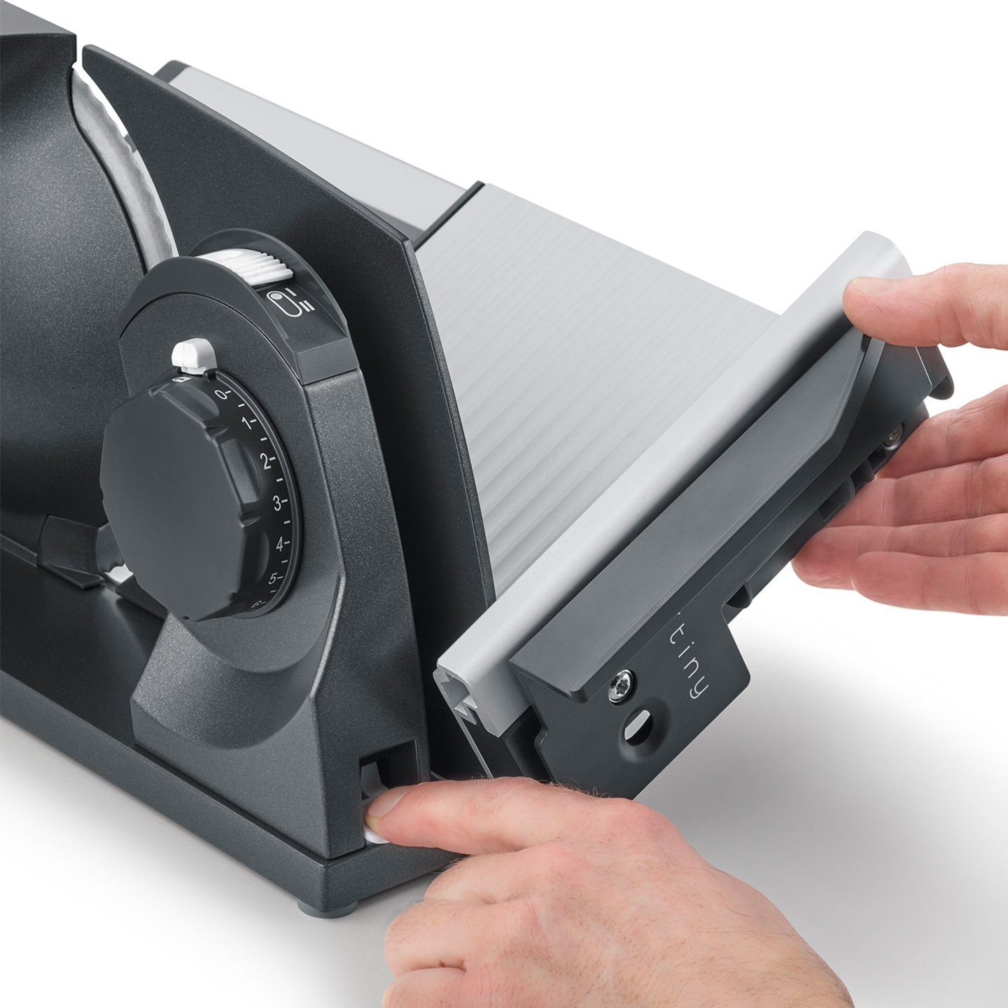 Close-up of an electric food slicer with controls and hands in use