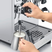 Persona che monta il latte con una macchina per espresso per fare un latte.