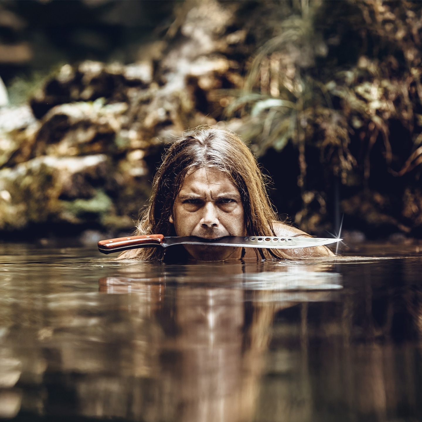Uomo con coltello in bocca nell'acqua