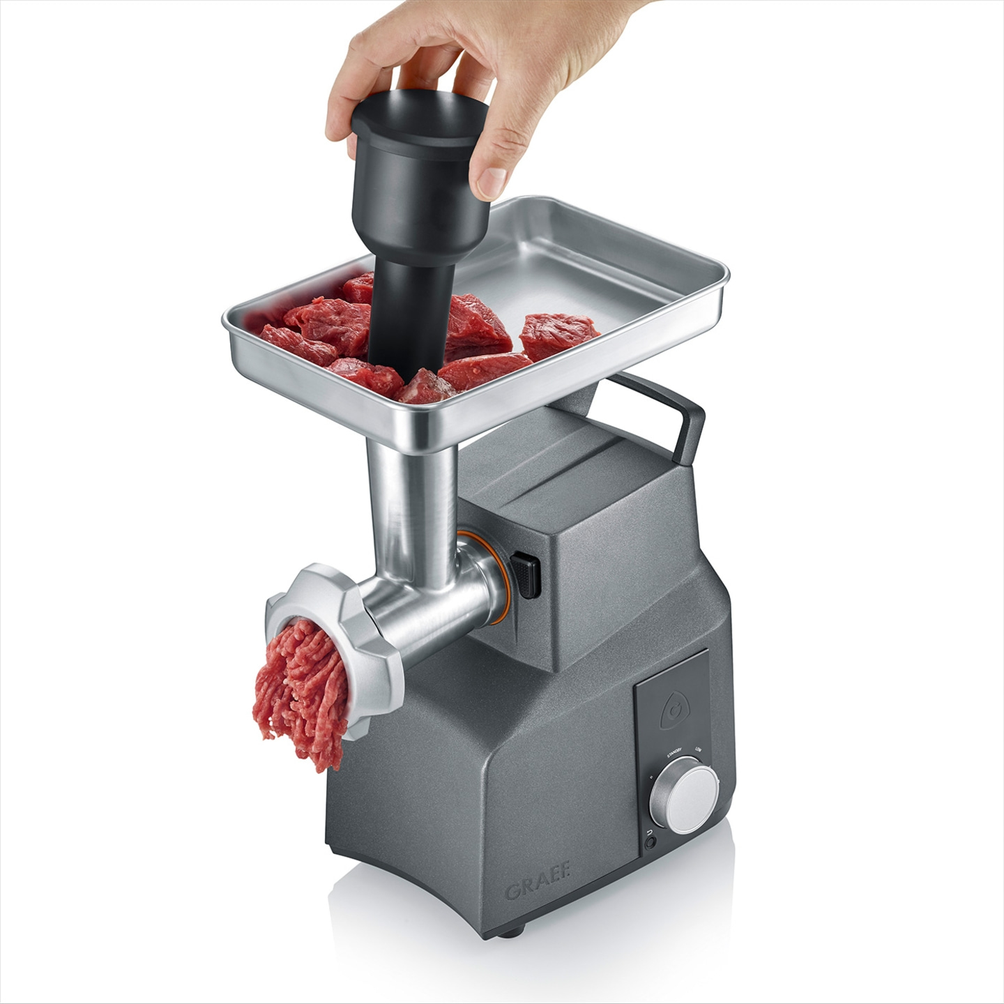 Meat grinder with meat and hand operating the pusher, gray machine, food processing
