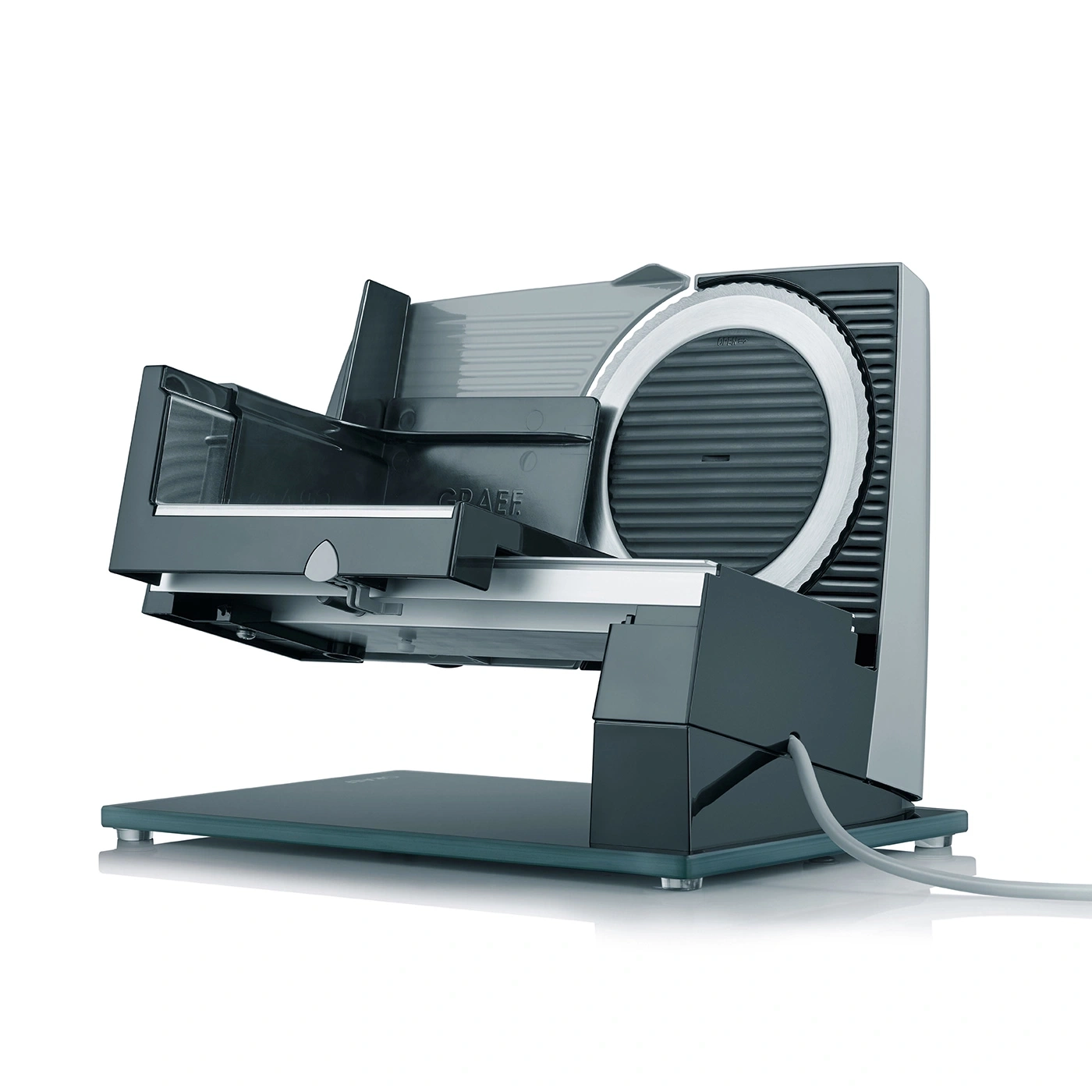 Electric Graef slicer, grey, with blade and food holder, on a glass base