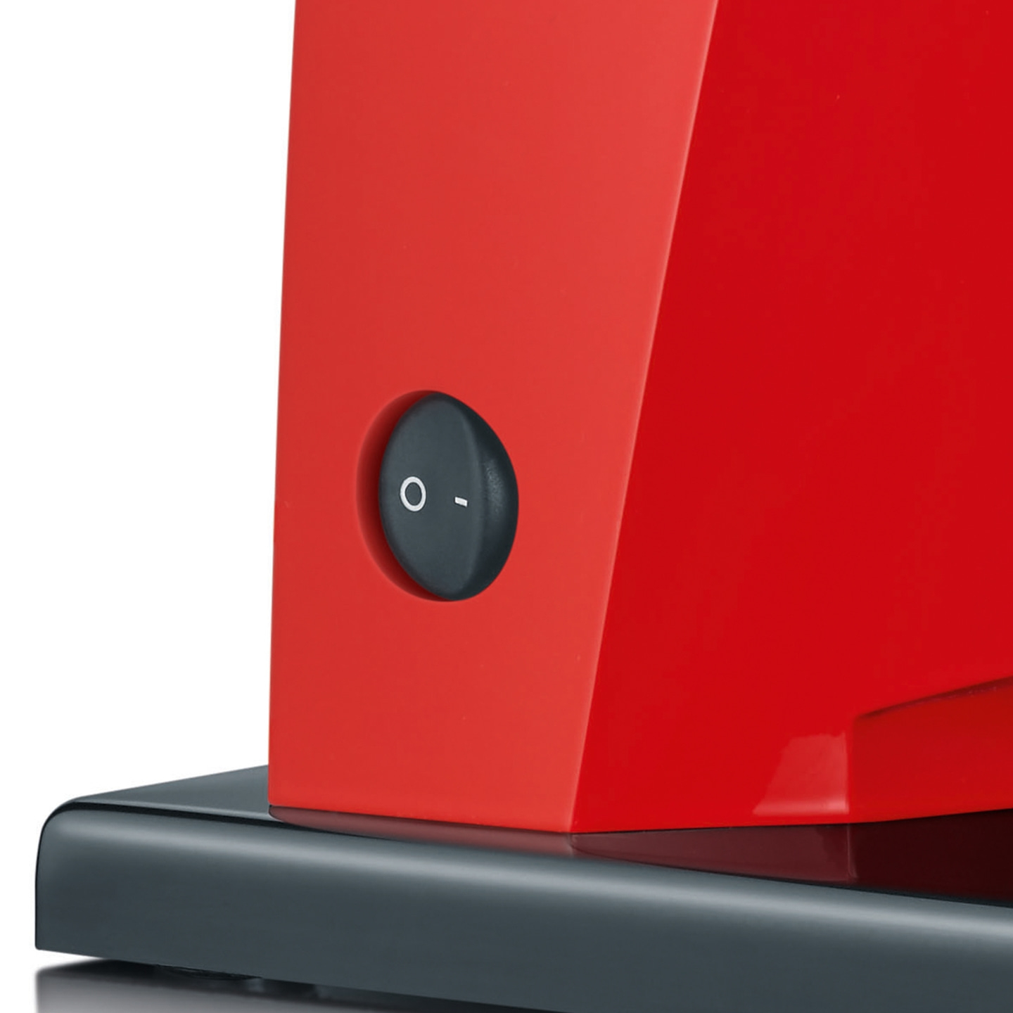 Appareil rouge avec un bouton noir, sur une base sombre, prise de vue rapprochée.