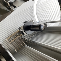 Close-up of a meat slicer with a black handle and a blade