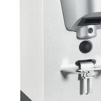 Gros plan d'un appareil argenté avec un bouton et des pièces métalliques.