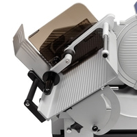 Close-up of a silver meat slicer with protective guards and handles, angled view