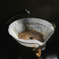 Eau chaude versée à travers un filtre à café dans une carafe en verre.