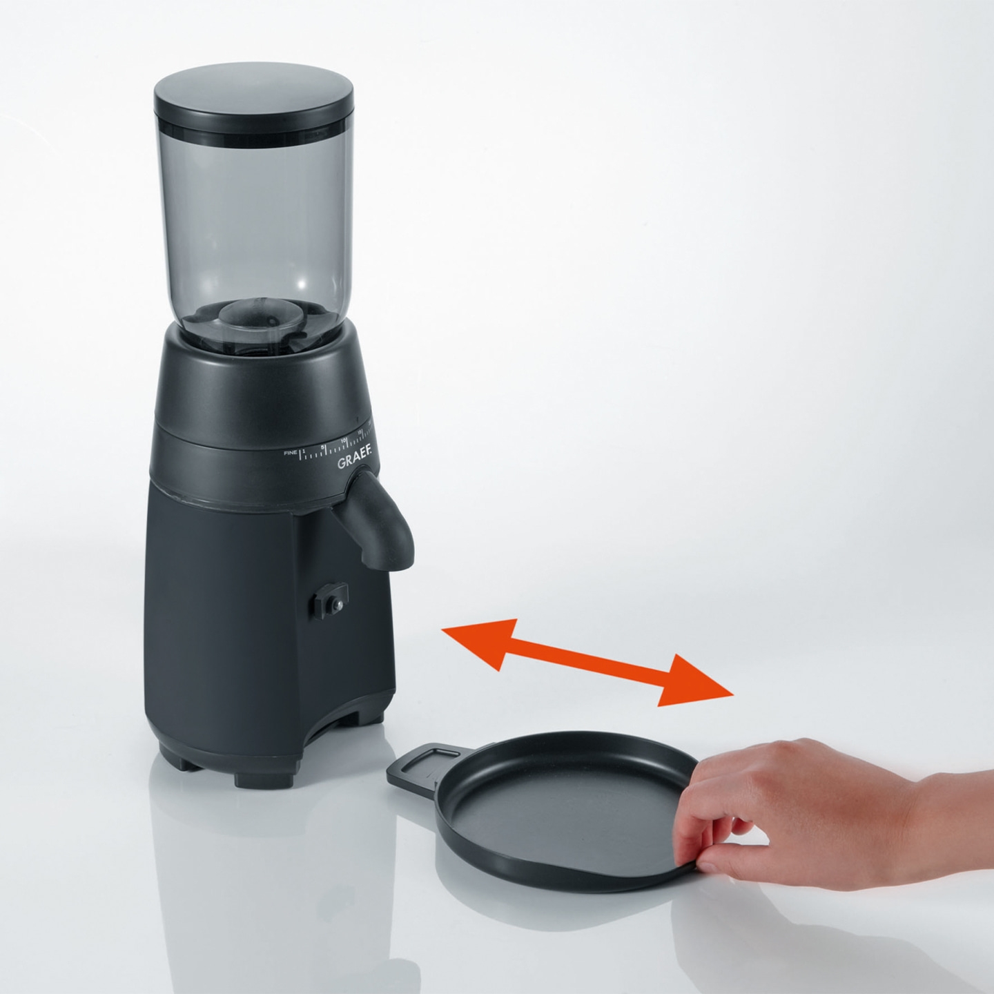 Coffee grinder with tray, arrow indicating movement, hand reaching for tray.