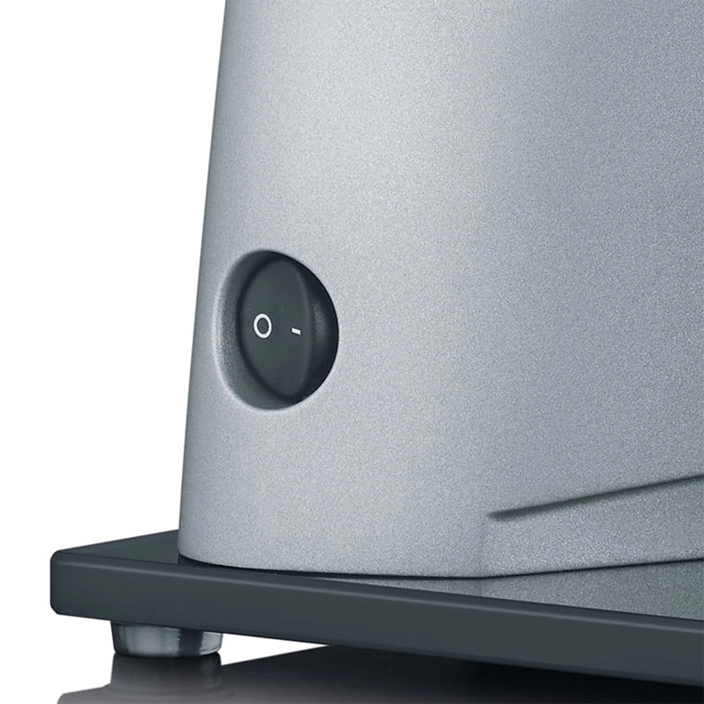 Primo piano di un elettrodomestico grigio con interruttore on/off e base scura.