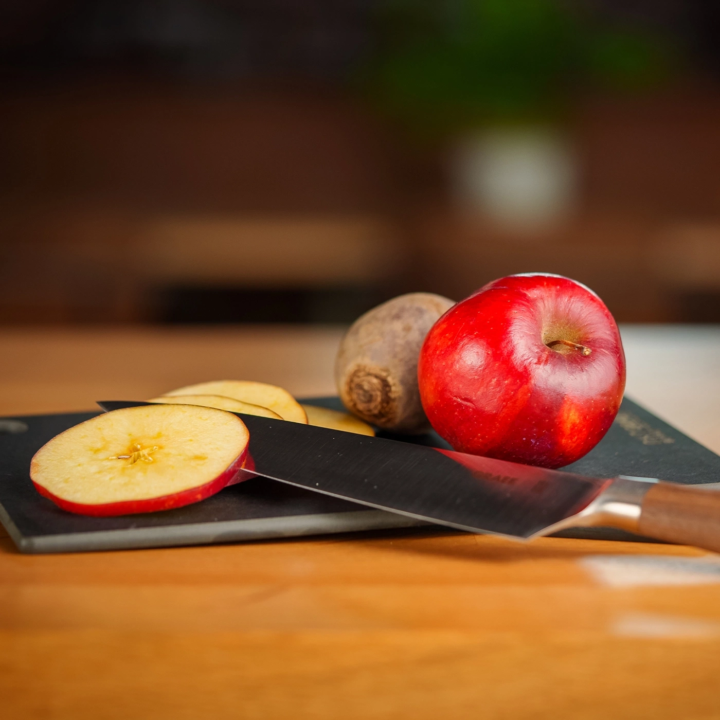 Mela, coltello e barbabietola su un tagliere di legno. Primo piano.
