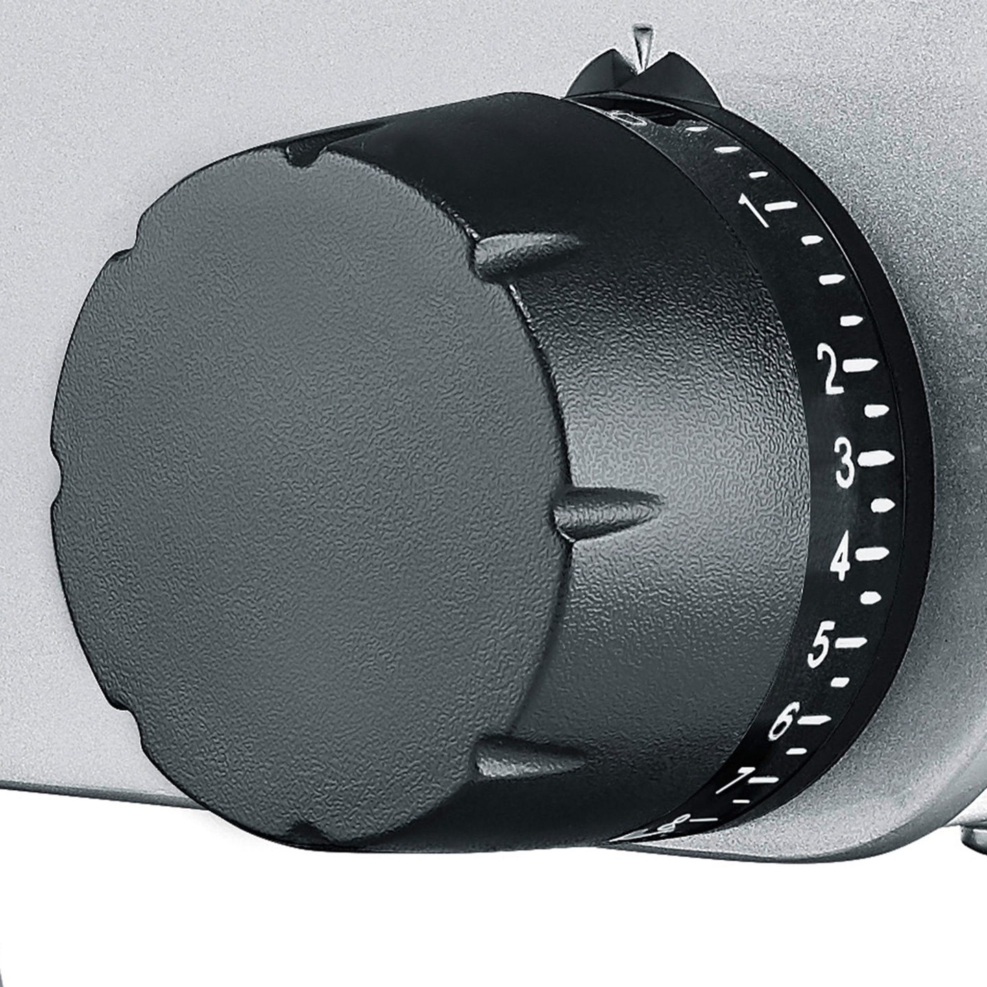 Primo piano di una manopola nera con numeri su sfondo argentato.