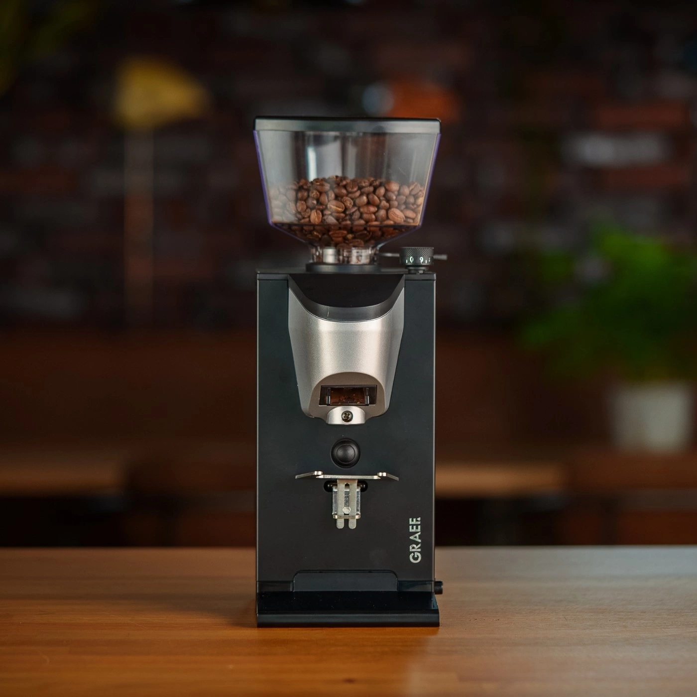Coffee grinder with beans on a wooden table, GRAEF logo visible.