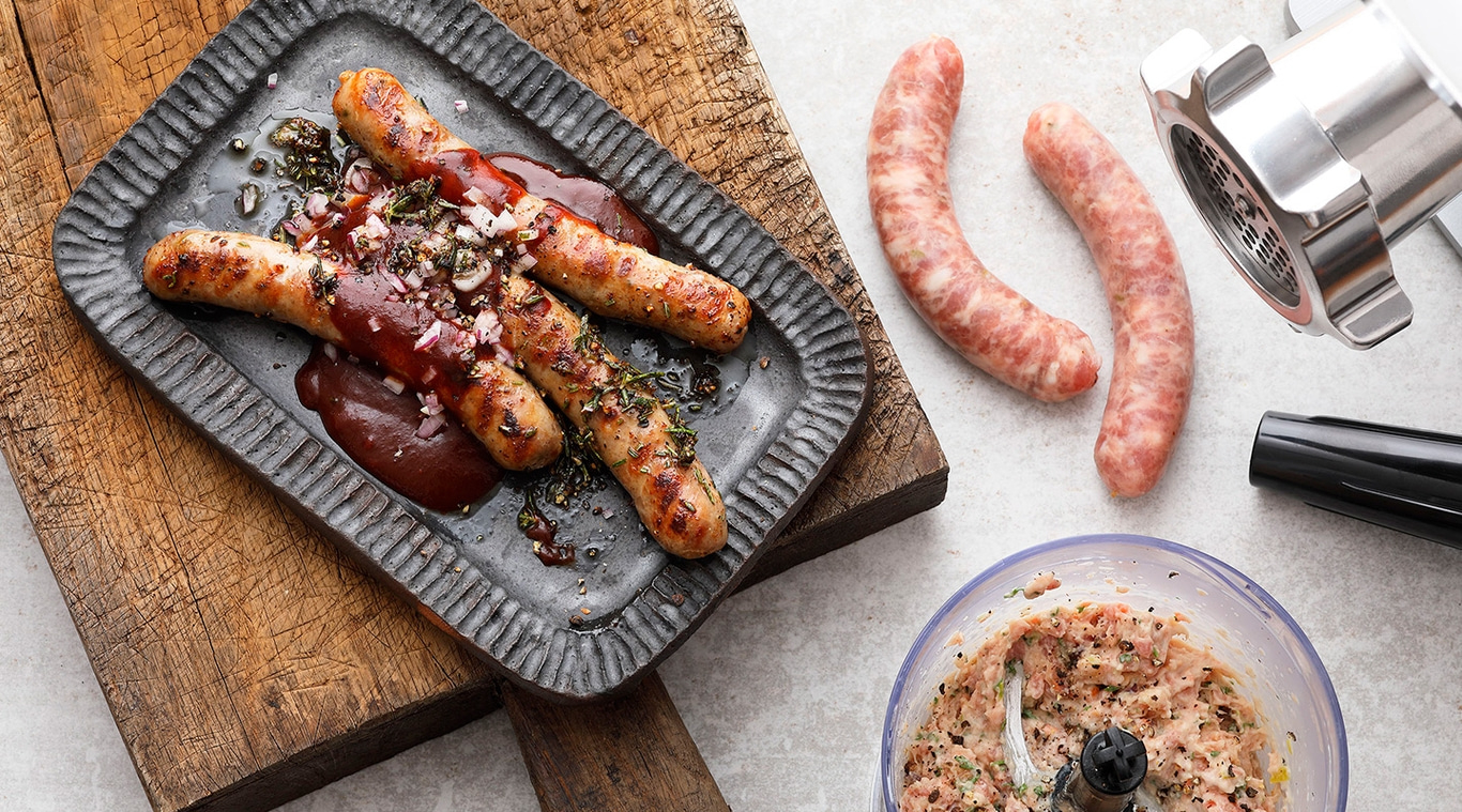 Salsicce grigliate su un piatto con salsa e ingredienti, ripresa ravvicinata.