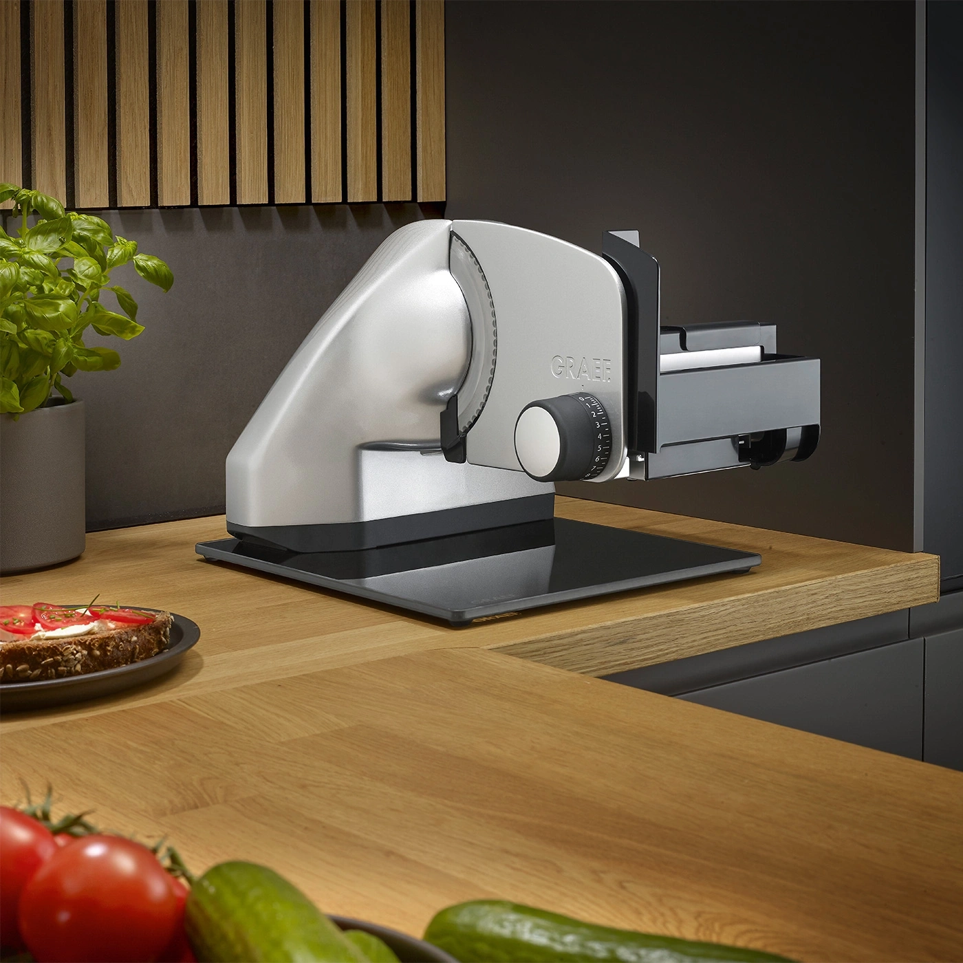 Affettatrice Graef su tavolo di legno con verdure e pane in primo piano
