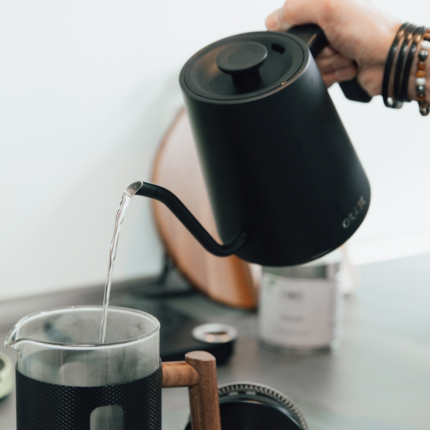 Black kettle pouring water into a coffee pot, close-up shot of the process.