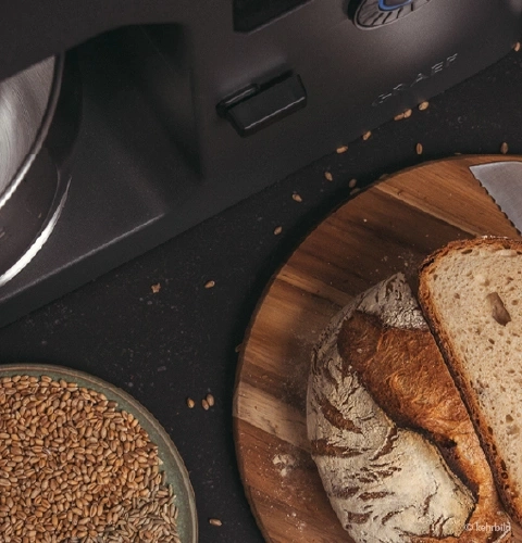 Close-up of bread, wheat, and a bread slicer machine.