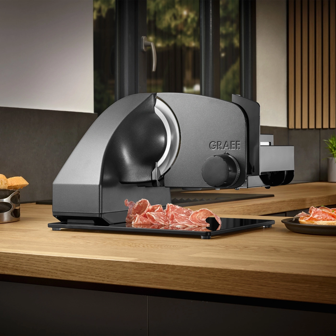 Affettatrice Graef su tavolo di legno con salumi e pane