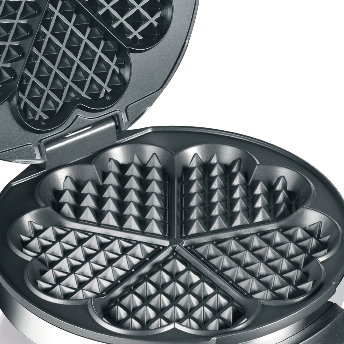 Close-up of an open waffle iron with heart-shaped indentations for cooking