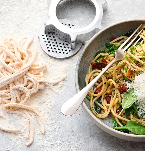 Pasta con ingredienti e forchetta in una ciotola, primo piano