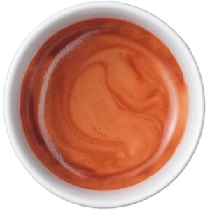 Primo piano di espresso in tazza bianca con consistenza cremosa