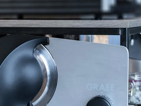 Close-up of a Graef slicer with a black knob and the word Graef on the side
