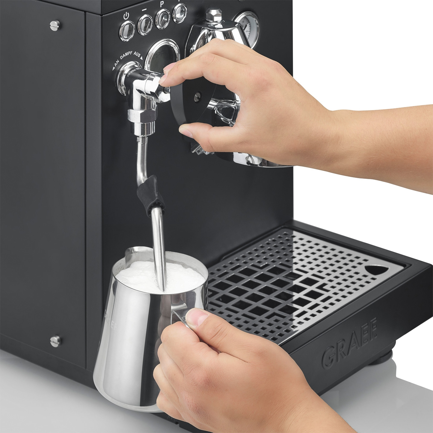 Person frothing milk with an espresso machine to make coffee.