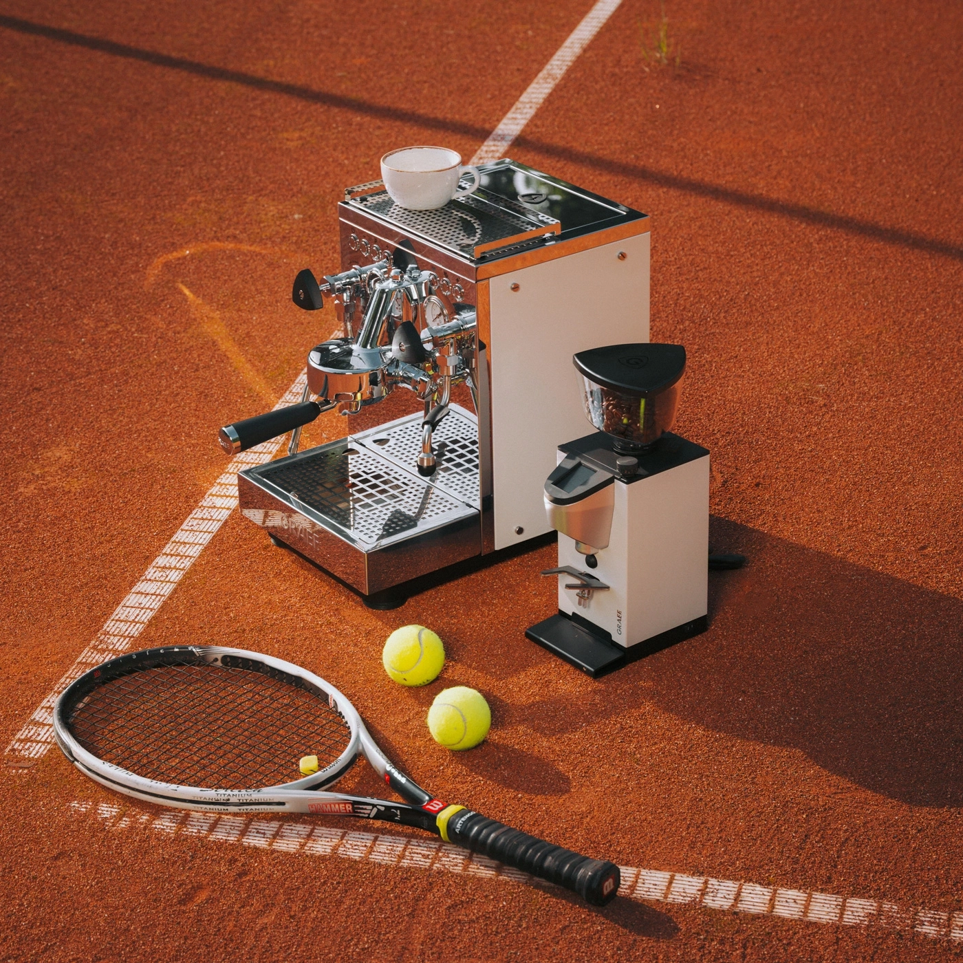 Espresso machine and tennis racket on clay court