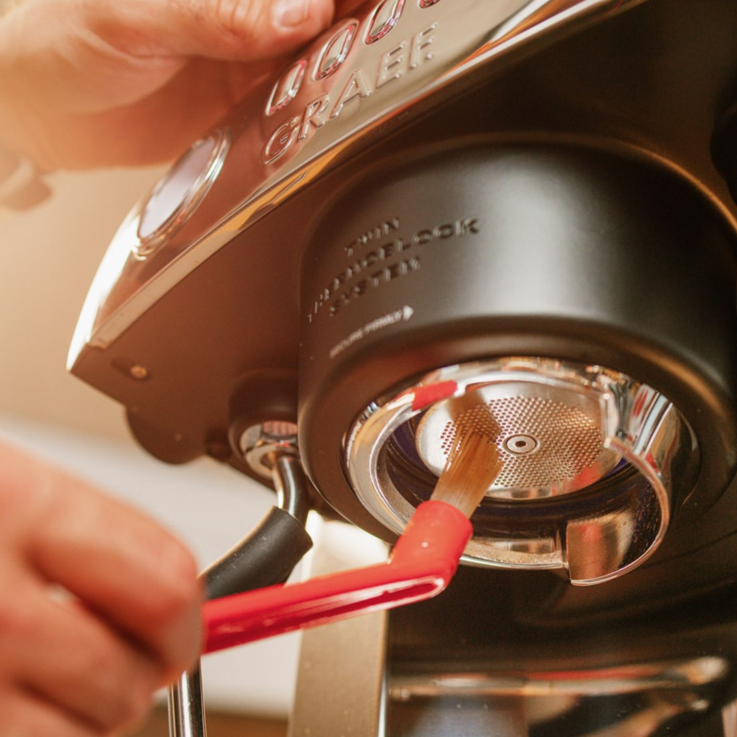 Nettoyage d'une machine à expresso avec une brosse. Gros plan de la machine.